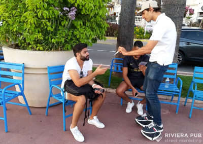 une hôtesse sur roller donne un flyer à un homme assis