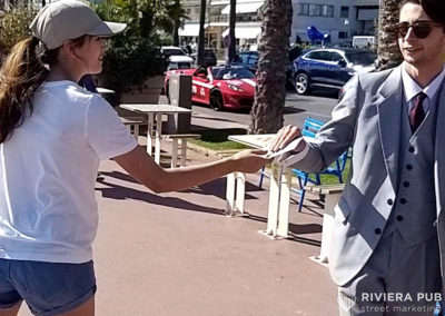 une hôtesse donne un flyer à un homme en costume