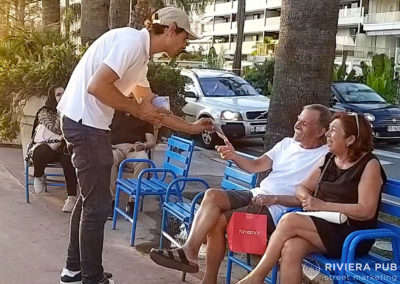 une hôtesse sur roller donne un flyer à un couple assis