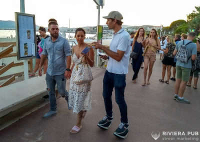 une hôtesse sur roller donne un flyer à des passants